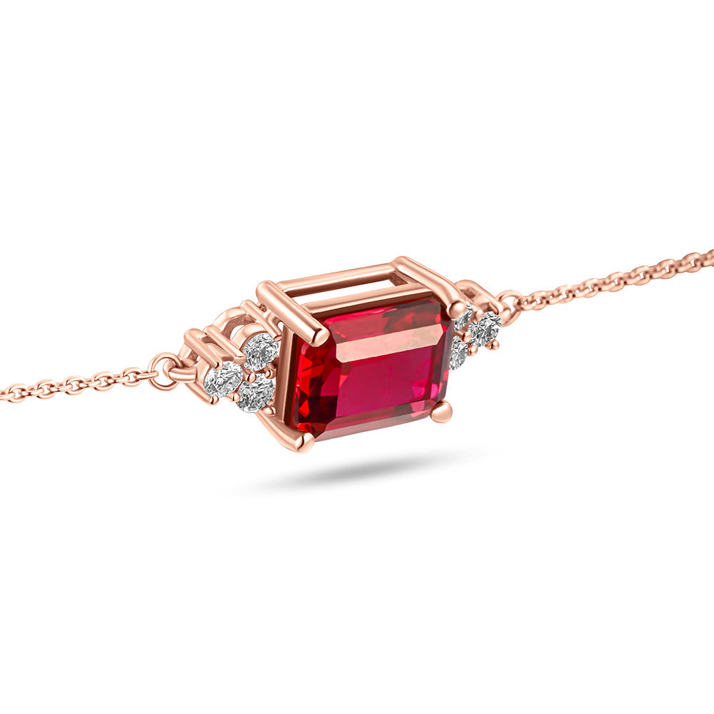 A rose gold bracelet featuring a prominent red ruby stone flanked by smaller white stones, possibly diamonds, set on a chain link.