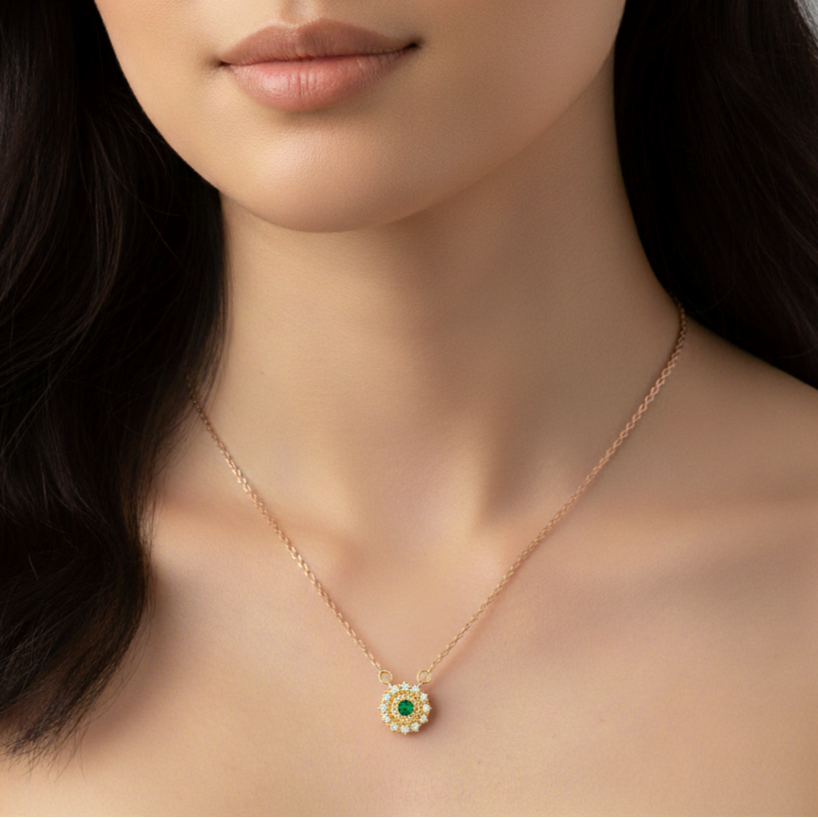 Woman wearing a gold necklace with a Emraled stone pendant 